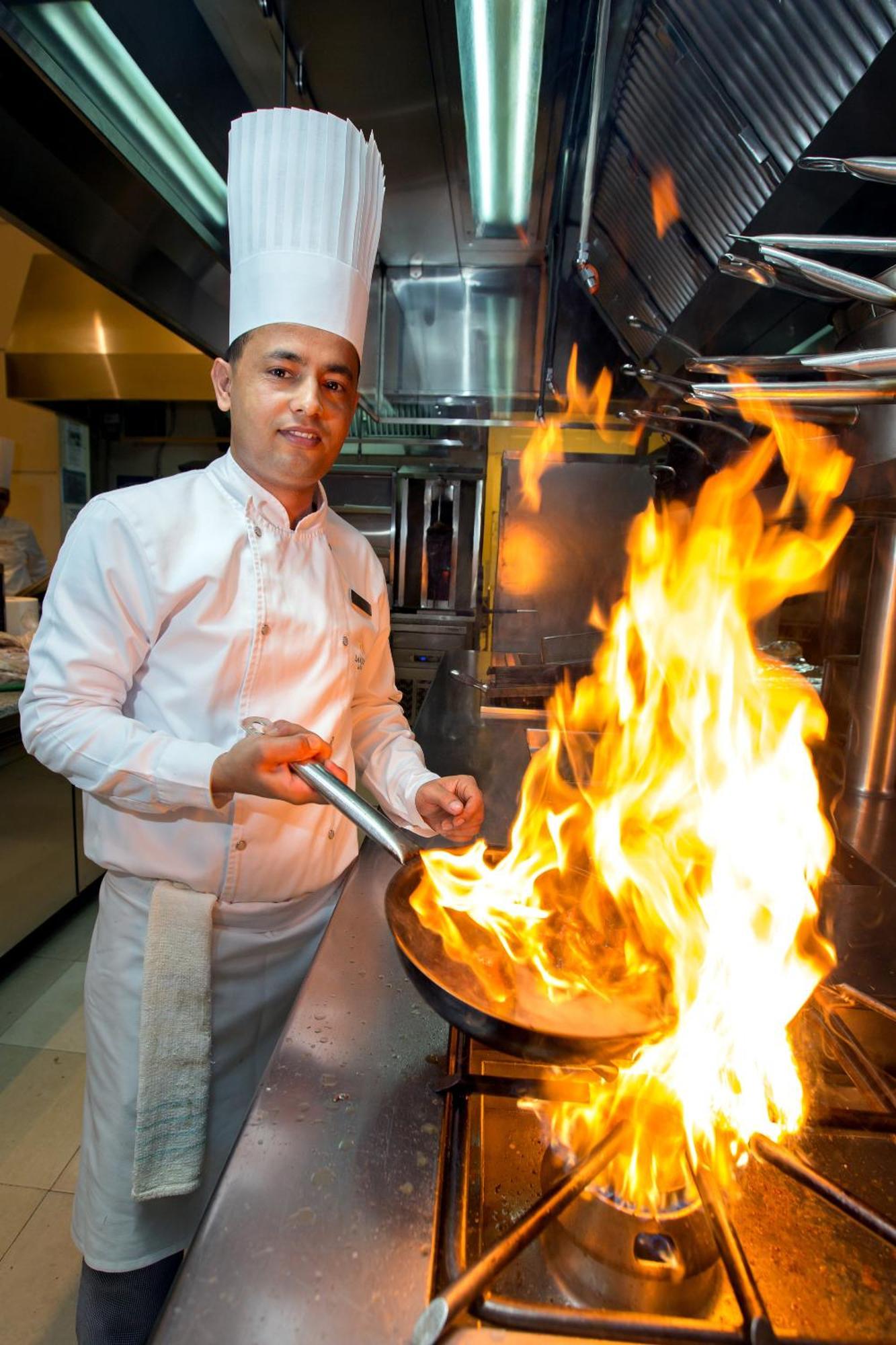 La Cigale Hotel Managed By Accor Doha Dış mekan fotoğraf A chef cooking with a flaming skillet